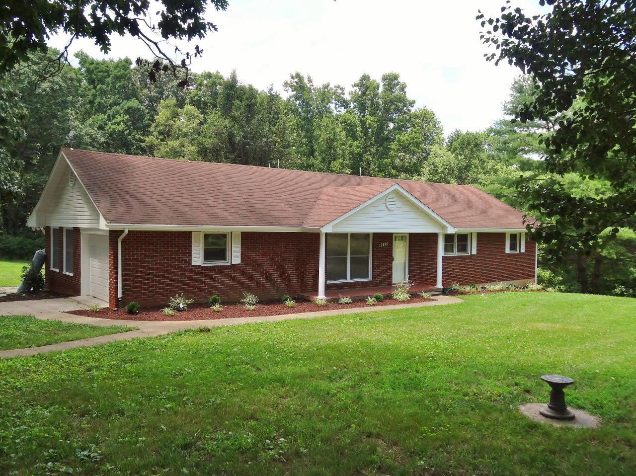 a front view of a house with a garden and trees