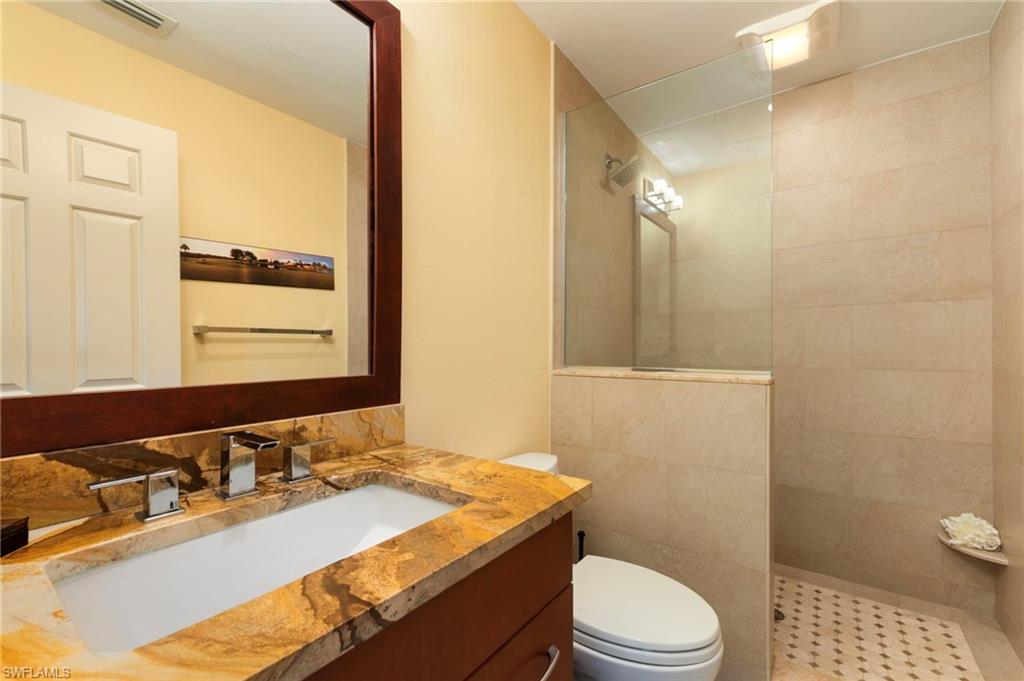 11737 Quail Village Way Naples, FL 34119 - Photo 26 of 50 a bathroom with a granite countertop sink toilet a mirror and shower