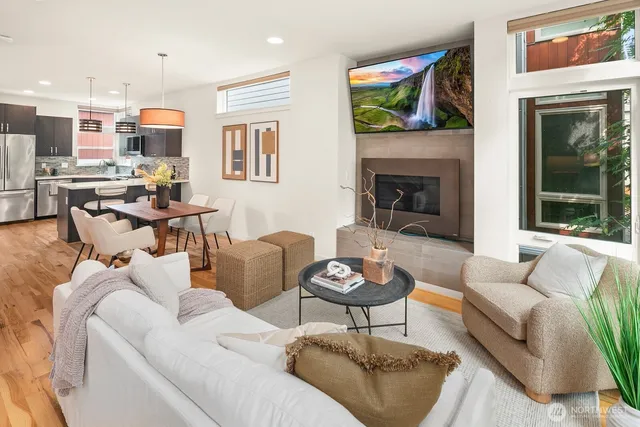 a open kitchen with stainless steel appliances granite countertop a stove top oven a refrigerator a kitchen island a dining table and chairs with wooden floor