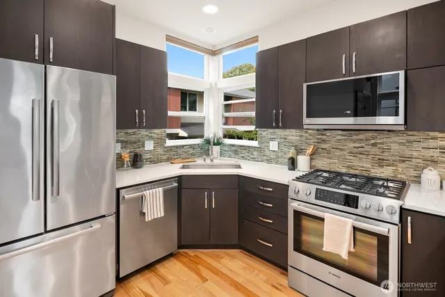 a kitchen with stainless steel appliances granite countertop a kitchen island a stove a dining table and chairs with wooden floor