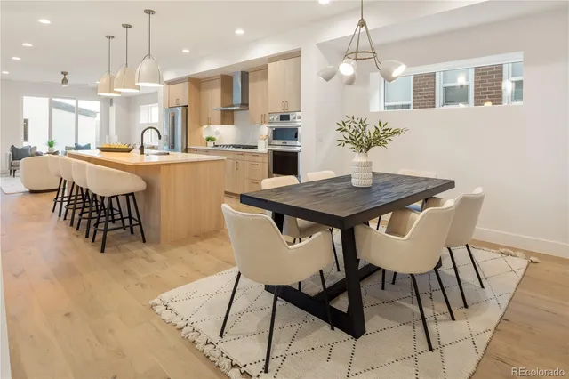 a kitchen with stainless steel appliances kitchen island granite countertop a dining table chairs and a refrigerator