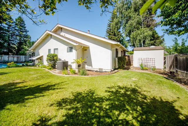 a view of a house with a yard and large tree