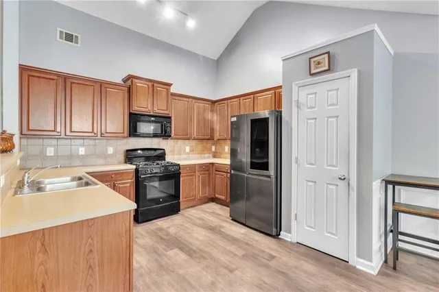a kitchen with granite countertop a refrigerator stove and sink