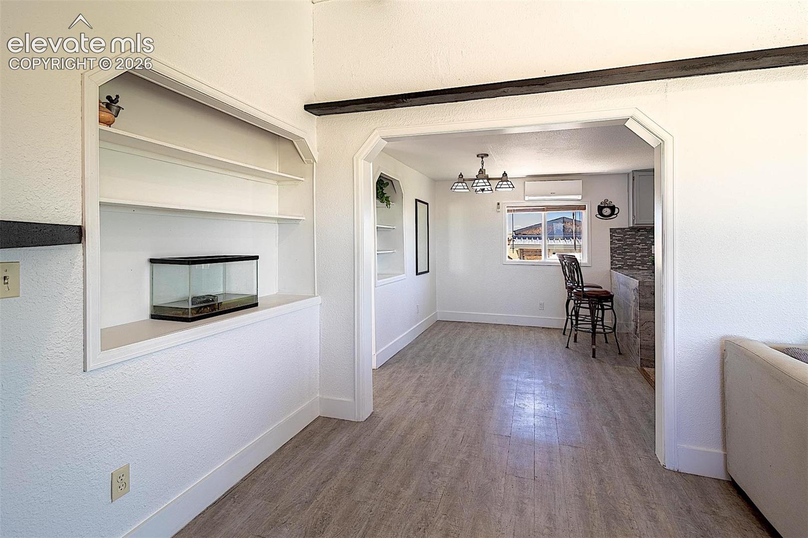 3425 Wiesner Road Calhan, CO 80808 - Photo 9 of 25 Dining area with baseboards, wood finished floors, a wall mounted AC, a chandelier, and built in shelves