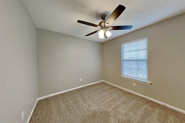 an empty room with a window and a fan