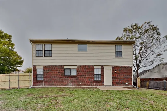 a brick house with a large tree in front of a house