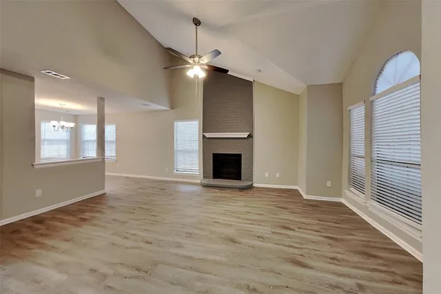 an empty room with wooden floor fireplace and windows
