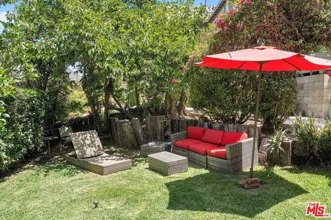 an outdoor sitting area with red umbrella and barbeque oven