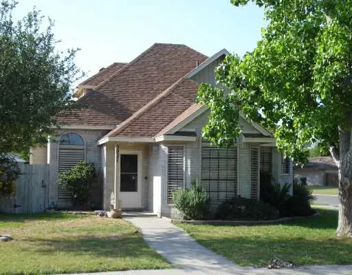 a view of a house with brick walls plants and large tree