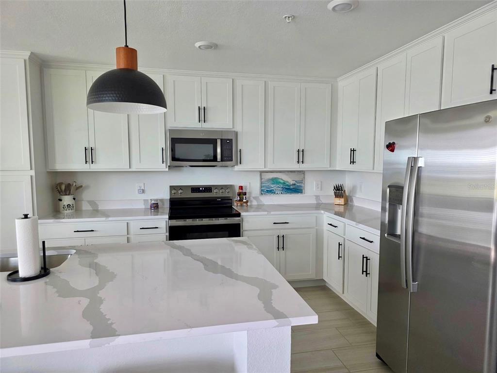 19116 Scallop Loop, Unit 303 Lakewood Ranch, FL 34211 - Photo 3 of 32 a kitchen with stainless steel appliances a stove a sink a refrigerator a stove a microwave and cabinets