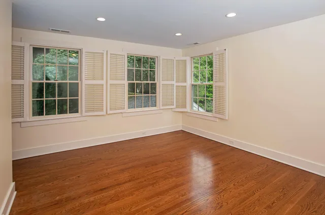 a view of an empty room with wooden floor and windows