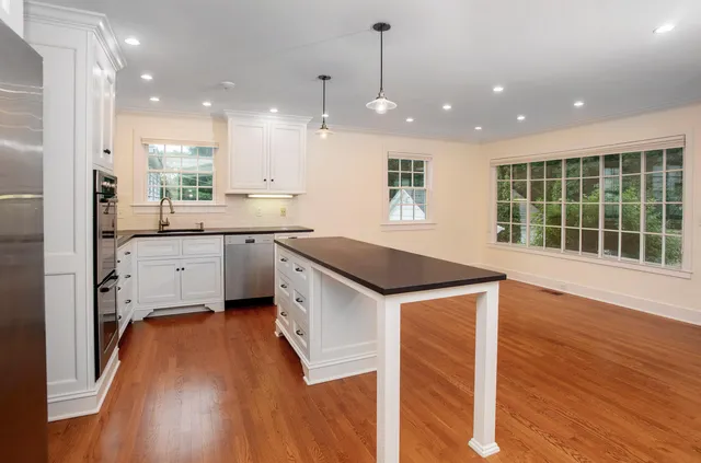 a kitchen with a sink a stove a refrigerator and white cabinets with wooden floor