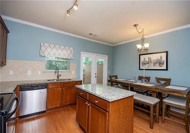 a kitchen with a stove a sink dishwasher a kitchen island with wooden cabinets and floor