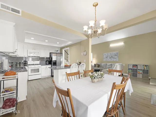 a view of a dining room and livingroom with furniture wooden floor a chandelier