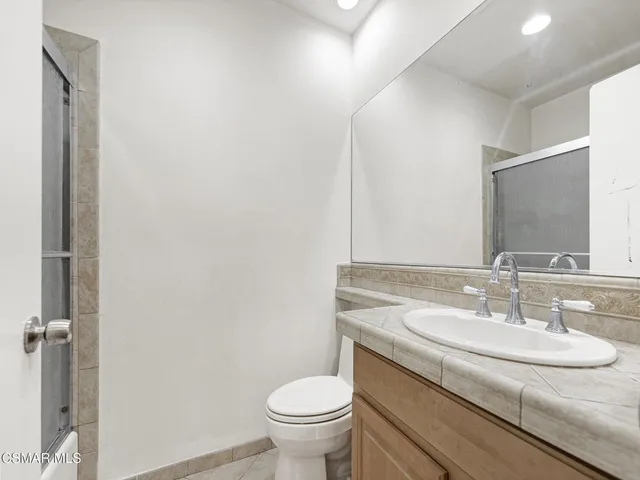 a bathroom with a granite countertop sink a toilet and a mirror