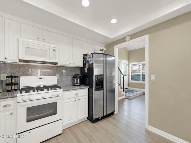 a kitchen with a refrigerator stove and wooden cabinets