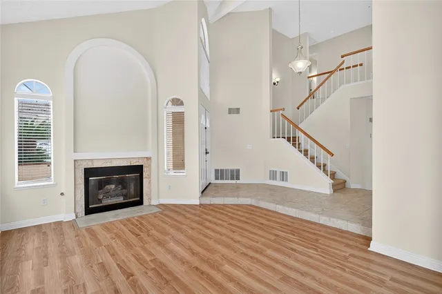 a view of an empty room with wooden floor fireplace and a window