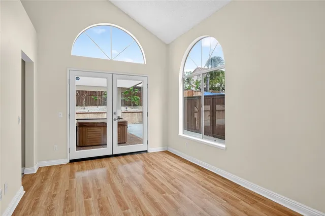 an empty room with wooden floor cabinet and windows