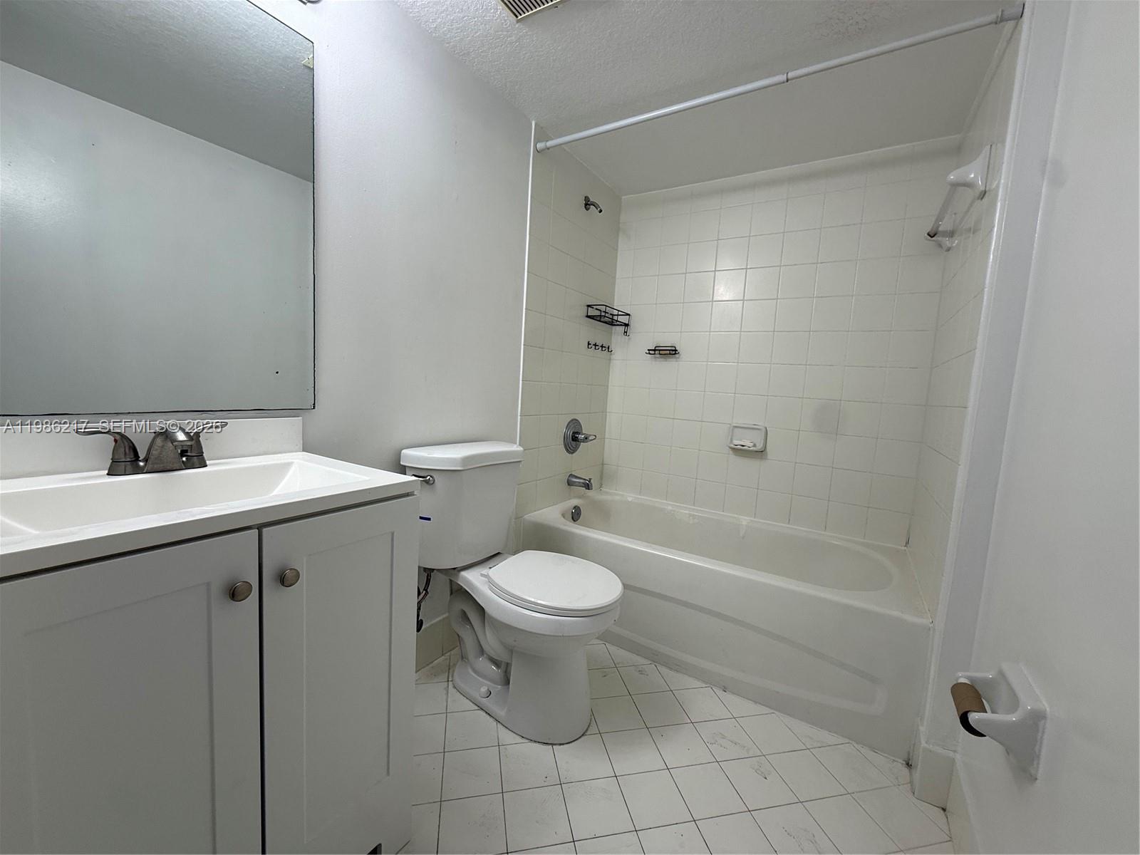 940 Northeast 33rd Terrace, Unit 101 Homestead, FL 33033 - Photo 15 of 20 a bathroom with a granite countertop toilet a sink and mirror