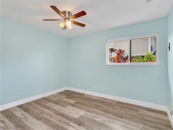 a view of an empty room with window and wooden floor