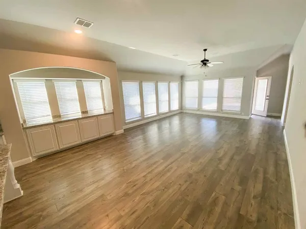 an empty room with wooden floor and windows