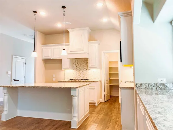 a kitchen with kitchen island granite countertop a sink a counter top space appliances and cabinets