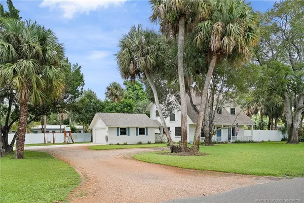a view of house with a yard and large trees
