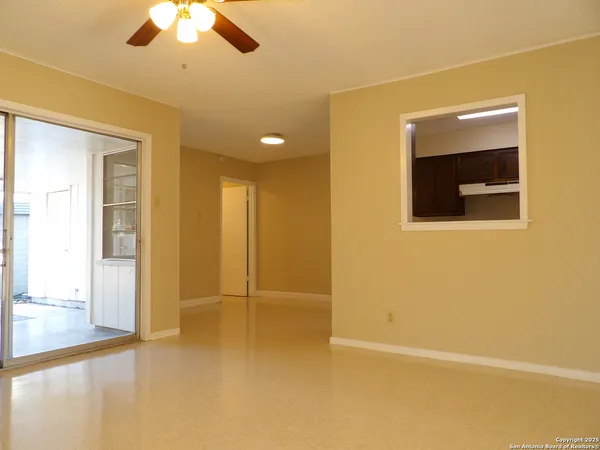 a view of an empty room with a chandelier fan