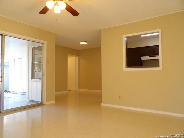 a view of an empty room with a chandelier fan
