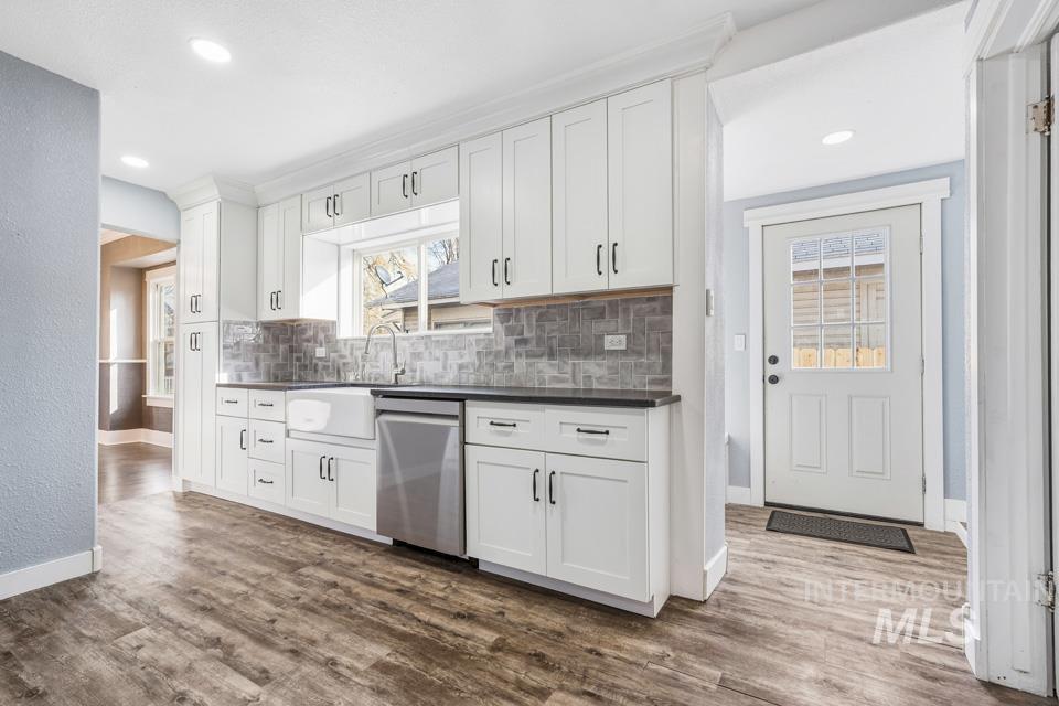 253 West Court Street Weiser, ID 83672 - Photo 11 of 35 Kitchen with white cabinetry, dark countertops, stainless steel dishwasher, dark wood-style floors, and recessed lighting