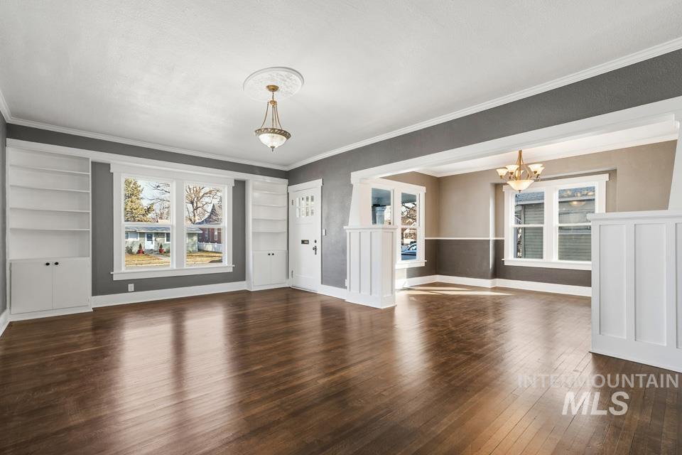 253 West Court Street Weiser, ID 83672 - Photo 2 of 35 Unfurnished living room with built in features, dark wood-style floors, crown molding, and a chandelier
