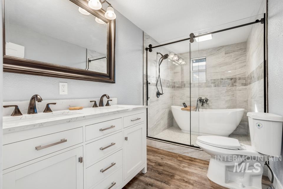 253 West Court Street Weiser, ID 83672 - Photo 22 of 35 Bathroom with double vanity, a freestanding tub, a stall shower, and dark wood-style floors