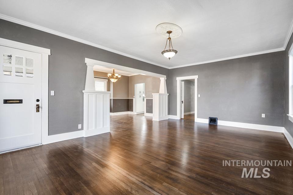 253 West Court Street Weiser, ID 83672 - Photo 3 of 35 Unfurnished dining area with dark wood-style flooring, ornamental molding, and hanging lights