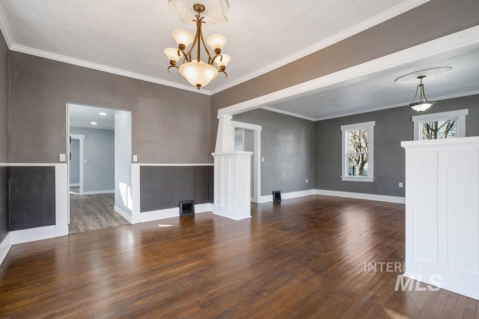 253 West Court Street Weiser, ID 83672 - Photo 7 of 35 Unfurnished dining area featuring dark wood-type flooring, crown molding, and hanging lights