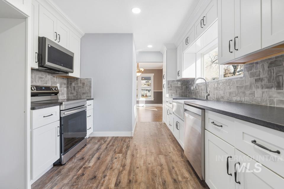 253 West Court Street Weiser, ID 83672 - Photo 10 of 35 Kitchen featuring dark countertops, stainless steel appliances, white cabinets, and dark wood finished floors