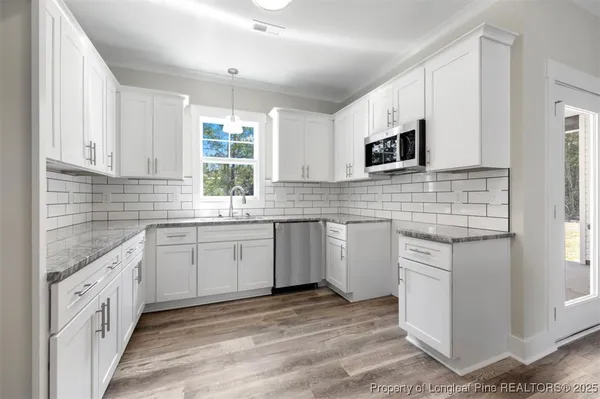 a kitchen with granite countertop white cabinets white appliances a sink and a window