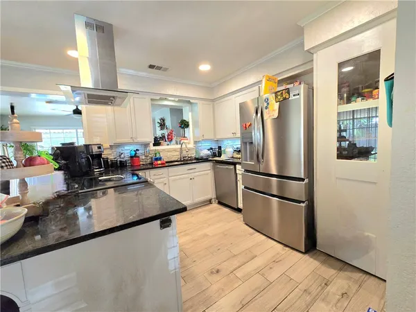 a kitchen with stainless steel appliances granite countertop a refrigerator sink and white cabinets
