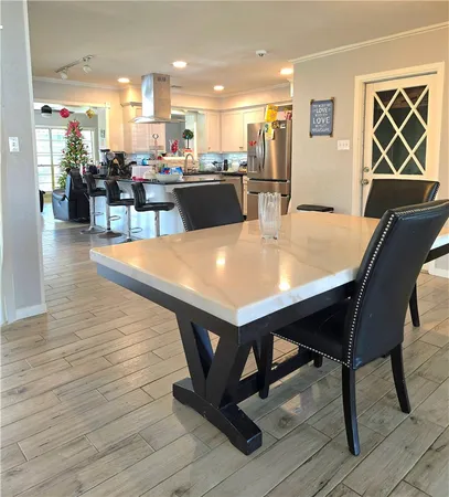 a dining table with stainless steel appliances kitchen island granite countertop furniture wooden floor and a kitchen view