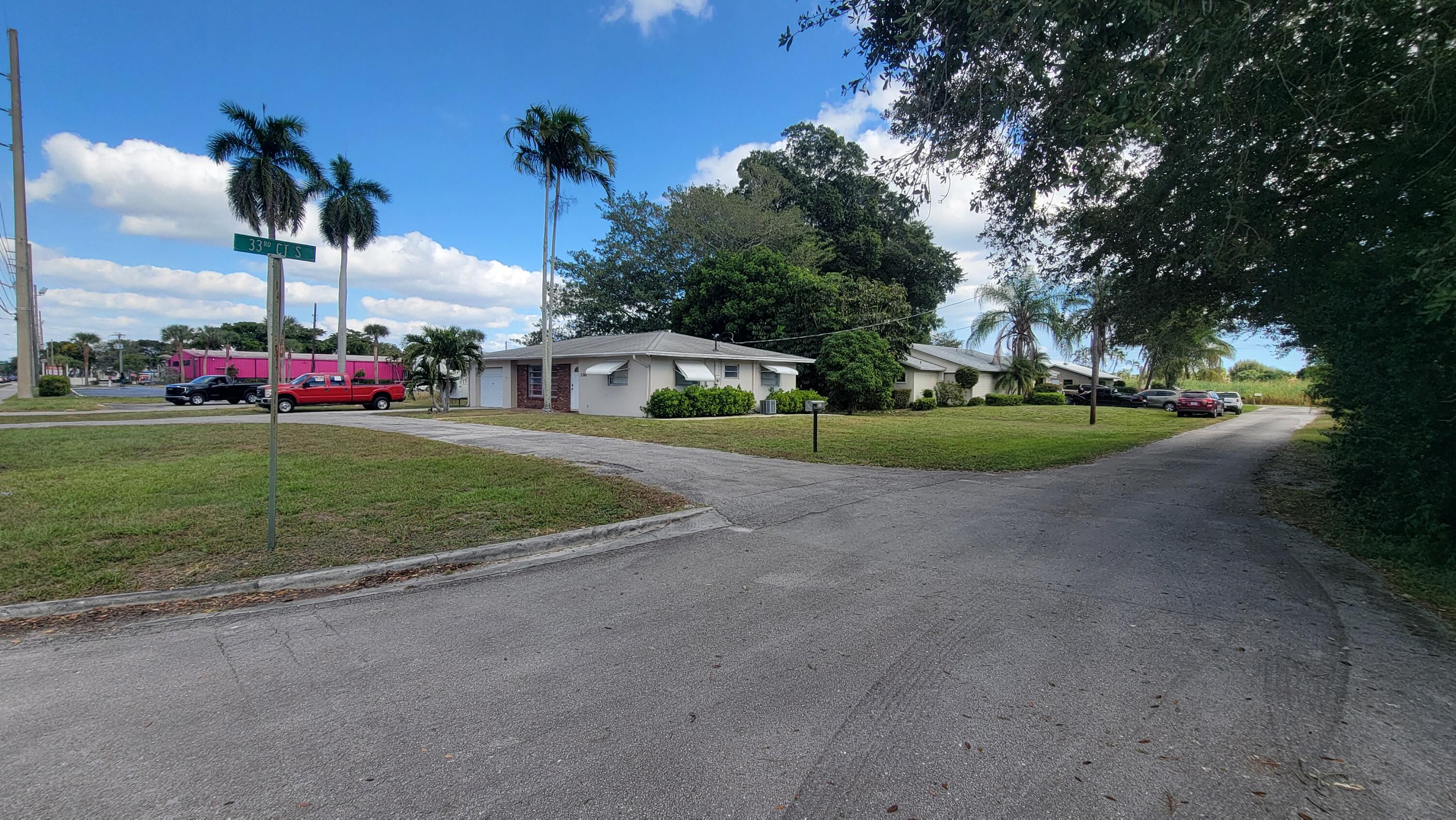 3340 Jog Road Greenacres, FL 33467 - Photo 2 of 20 a view of a house with a big yard and palm trees