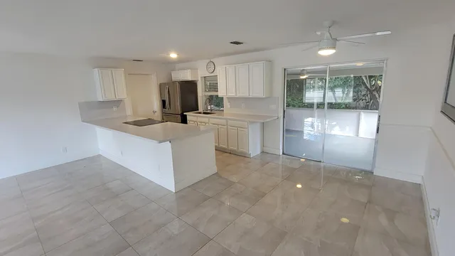 a large white kitchen with a stove a sink a refrigerator and a cabinets