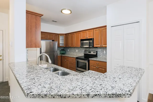 a kitchen with stainless steel appliances granite countertop a refrigerator a stove top oven and a sink