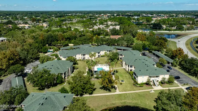 an aerial view of a residential houses with outdoor space and trees all around