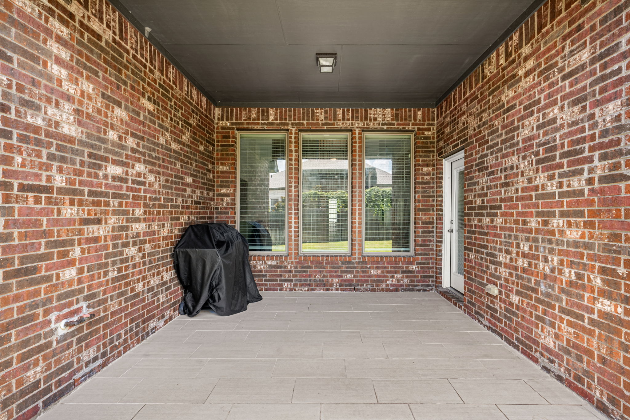 20813 Carries Ranch Road Pflugerville, TX 78660 - Photo 32 of 40 Rich brick walls and tiled flooring highlight this covered outdoor living space.