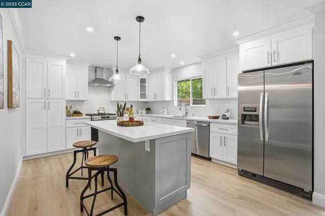 a kitchen with kitchen island a refrigerator a sink a stove and chairs