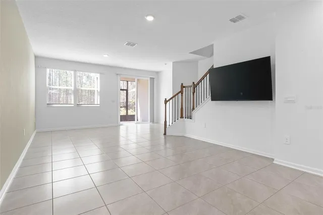 a view of an empty room with a window and a kitchen