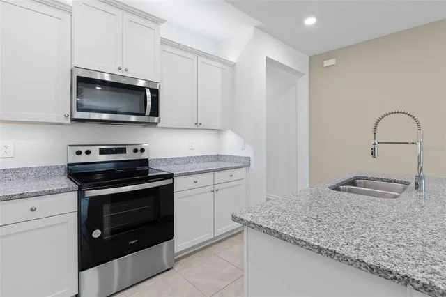 a kitchen with granite countertop white cabinets stainless steel appliances and a sink
