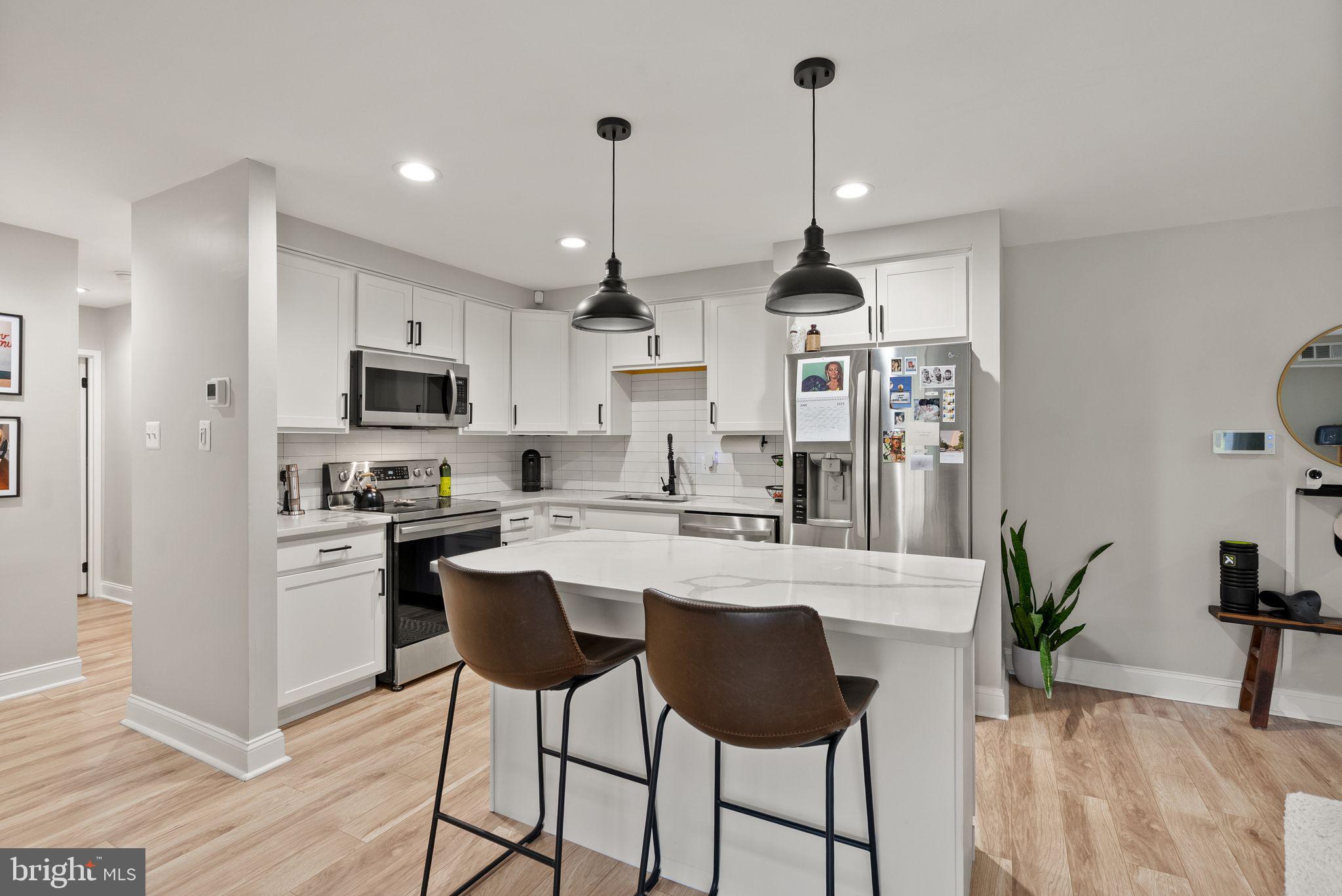 6137 Edsall Road, Unit L Alexandria, VA 22304 - Photo 13 of 36 a kitchen with stainless steel appliances kitchen island granite countertop a stove a sink a refrigerator a dining table and chairs with wooden floor