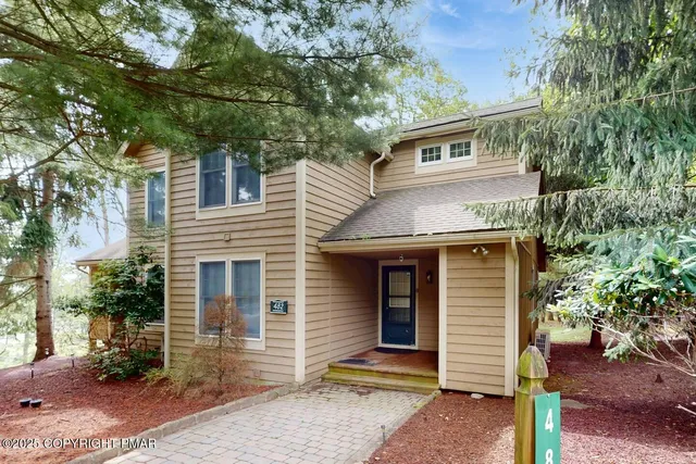 a front view of a house with a tree