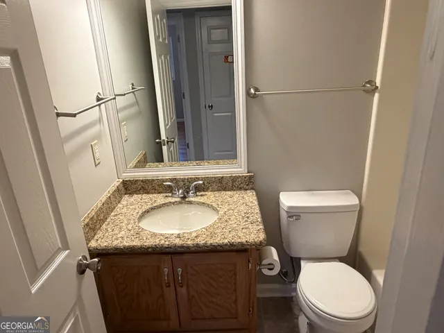 a bathroom with a granite countertop toilet sink and mirror