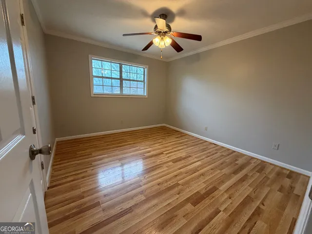 a view of empty room with wooden floor and fan